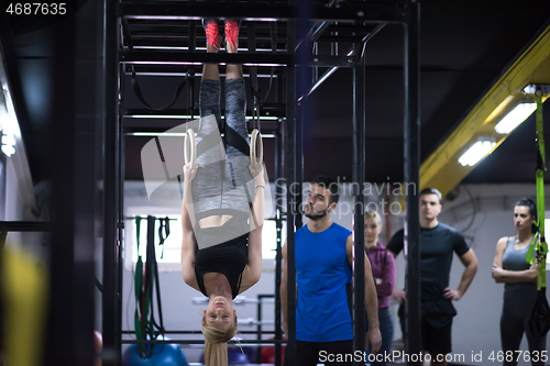 Image of woman working out with personal trainer on gymnastic rings