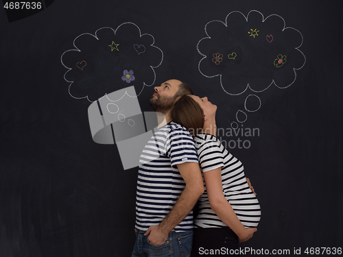 Image of pregnant couple posing against black chalk drawing board