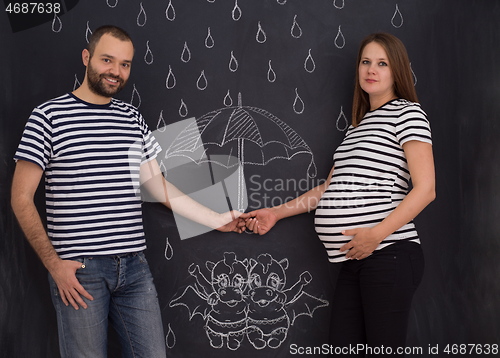 Image of pregnant couple drawing their imaginations on chalk board