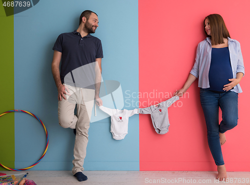 Image of young couple holding baby bodysuits