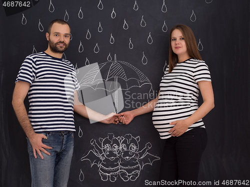 Image of pregnant couple drawing their imaginations on chalk board