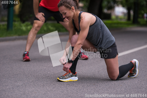 Image of sporty woman tying running shoes laces