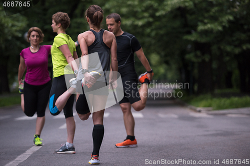 Image of runners team warming up and stretching before morning training