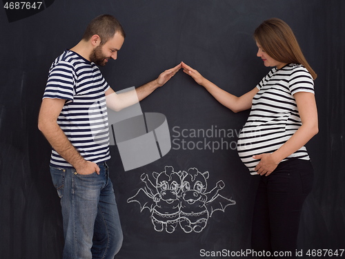 Image of pregnant couple drawing their imaginations on chalk board