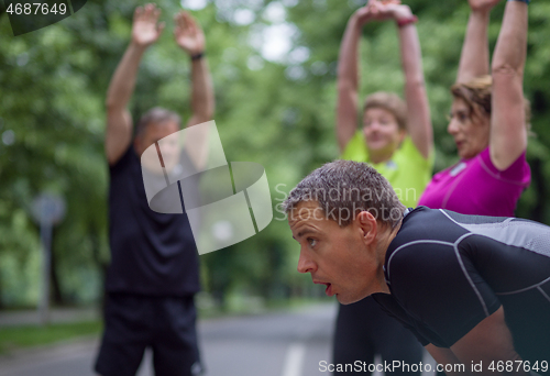 Image of runners team warming up and stretching before morning training