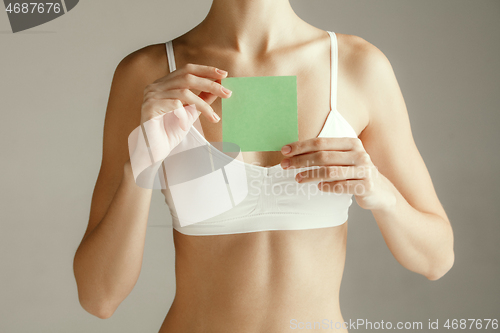 Image of Young adult woman holding empty paper card for sign or symbol.