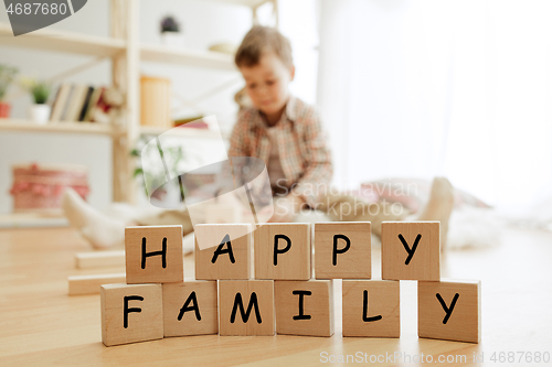 Image of Wooden cubes with words HAPPY FAMILY in hands of little boy