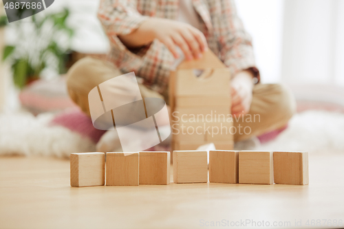 Image of Little child sitting on the floor. Pretty boy palying with wooden cubes at home