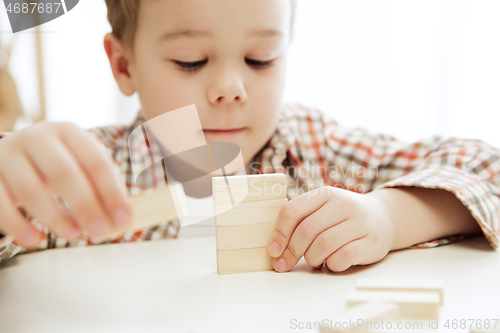 Image of Little child sitting on the floor. Pretty boy palying with wooden cubes at home