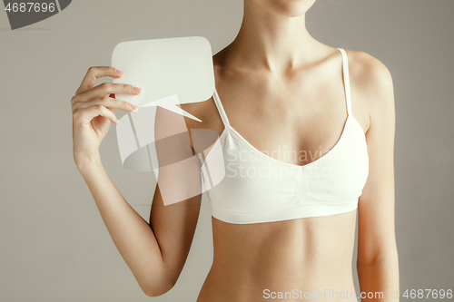 Image of Young adult woman holding empty paper card for sign or symbol.