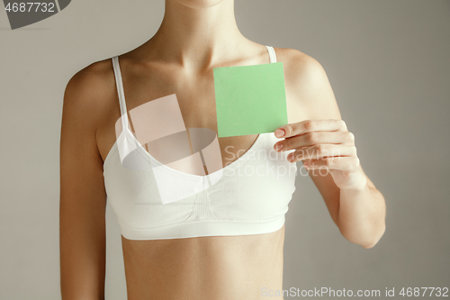 Image of Young adult woman holding empty paper card for sign or symbol.