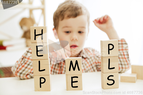 Image of Wooden cubes with words HELP ME PLS in hands of little boy