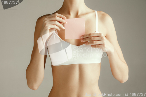 Image of Young adult woman holding empty paper card for sign or symbol.