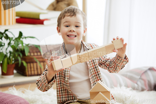 Image of Little child sitting on the floor. Pretty boy palying with wooden cubes at home