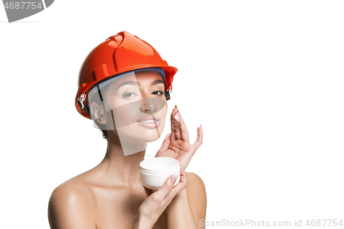 Image of Portrait of confident female worker in orange helmet