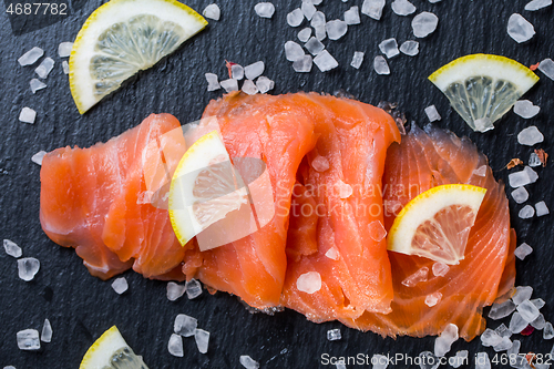 Image of Smoked salmon with lemon and sea salt on black background