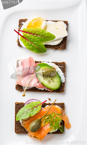 Image of Variation of healthy open sandwiches on Pumpernickel bread with vegetables, salmon, ham, herbs and soft cheese