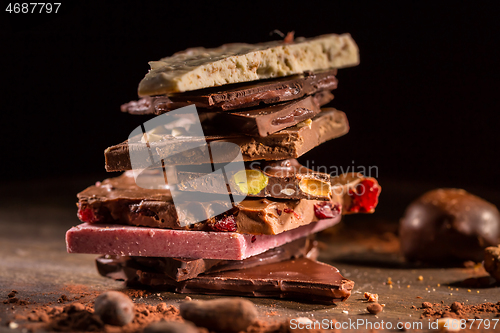 Image of Stack of assorted chocolate with cocoa and cocoa beans on black background