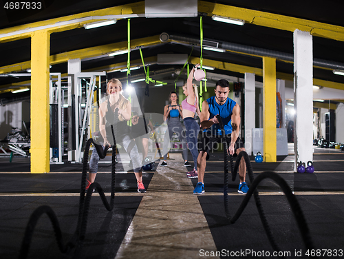 Image of sports couple doing battle ropes cross fitness exercise