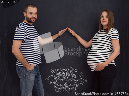 Image of pregnant couple drawing their imaginations on chalk board