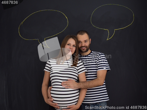 Image of pregnant couple posing against black chalk drawing board