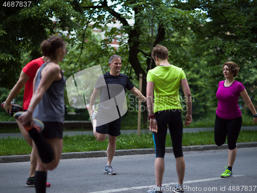 Image of runners team warming up and stretching before morning training