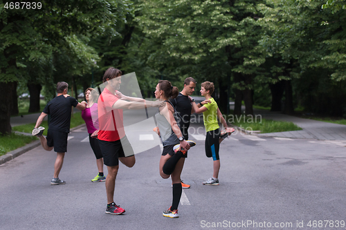 Image of runners team warming up and stretching before morning training