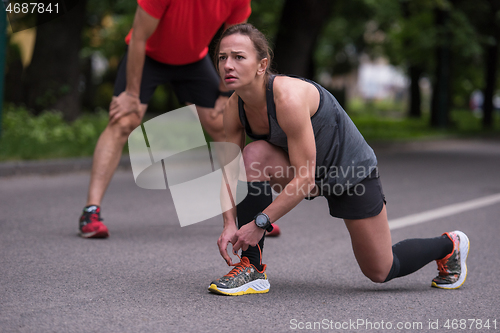 Image of sporty woman tying running shoes laces