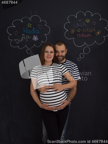 Image of pregnant couple posing against black chalk drawing board