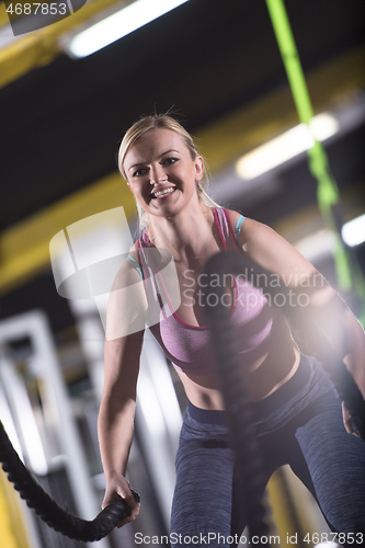 Image of athlete woman doing battle ropes cross fitness exercise