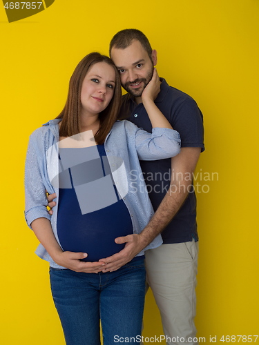 Image of pregnant couple  isolated over yellow background