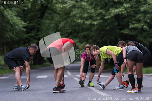 Image of runners team warming up and stretching before morning training