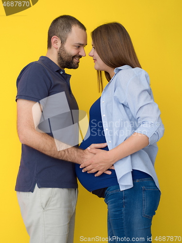 Image of pregnant couple  isolated over yellow background