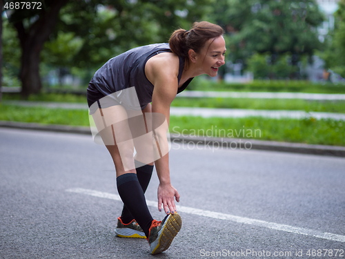 Image of female runner warming up and stretching before morning training