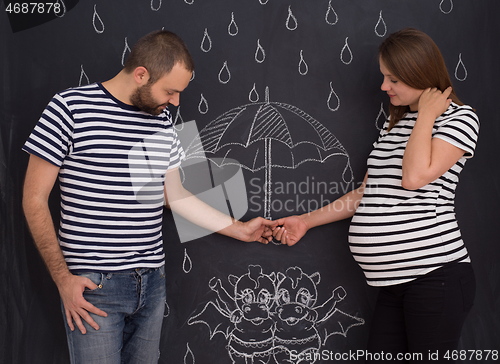 Image of pregnant couple drawing their imaginations on chalk board