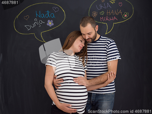 Image of pregnant couple posing against black chalk drawing board