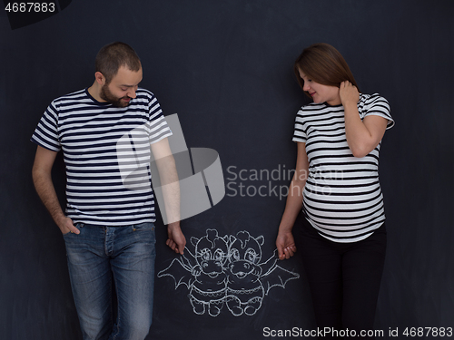 Image of pregnant couple drawing their imaginations on chalk board