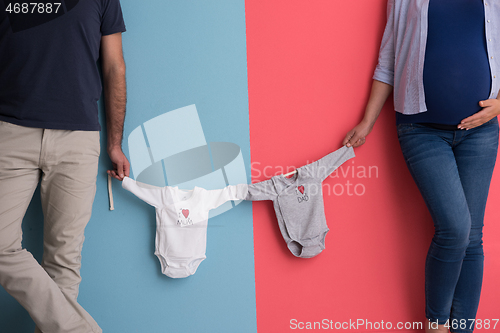 Image of young couple holding baby bodysuits