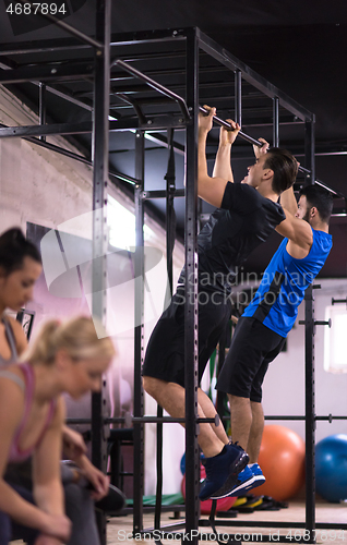 Image of young athletes doing pull ups on the horizontal bar