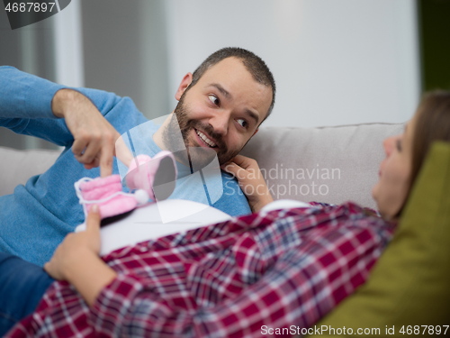 Image of young pregnant couple relaxing on sofa