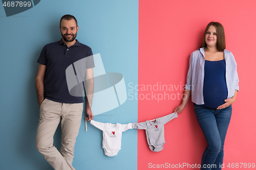 Image of young couple holding baby bodysuits