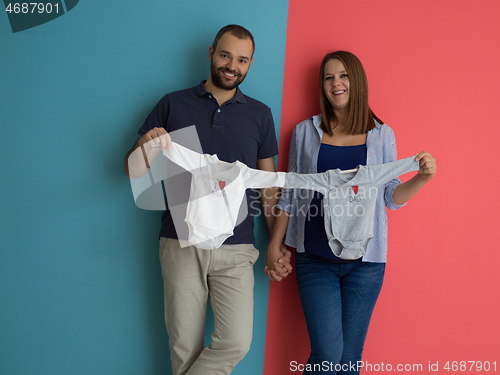 Image of young couple holding baby bodysuits