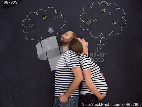 Image of pregnant couple posing against black chalk drawing board