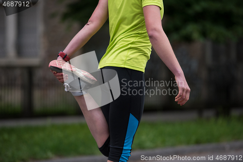 Image of female runner warming up and stretching before morning training