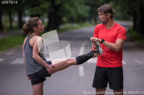 Image of runners team warming up and stretching before morning training