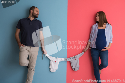 Image of young couple holding baby bodysuits