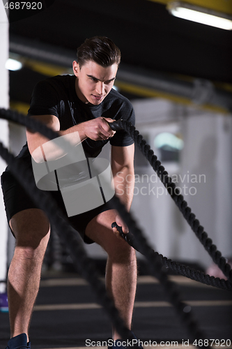 Image of athlete man doing battle ropes cross fitness exercise