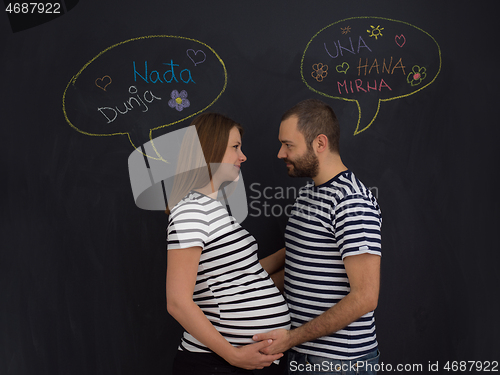 Image of pregnant couple posing against black chalk drawing board