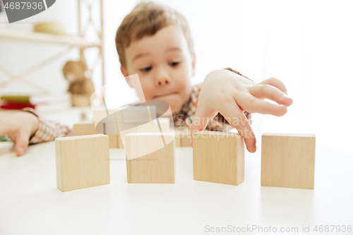 Image of Little child sitting on the floor. Pretty boy palying with wooden cubes at home