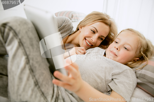 Image of Young mother and her little daughter hugging and kissing on bed